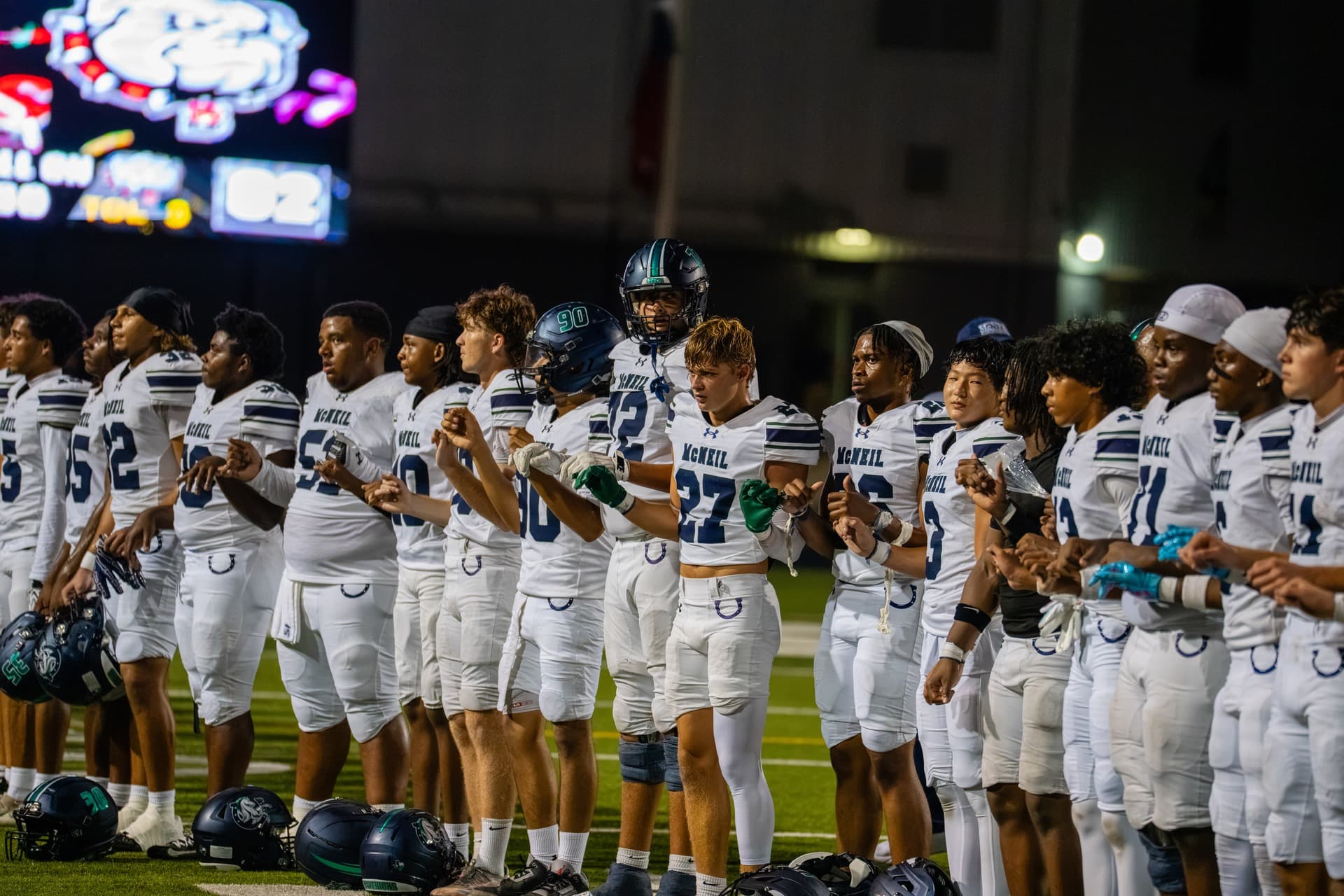 McNeil Mavericks football team lined up arm in arm along the sideline